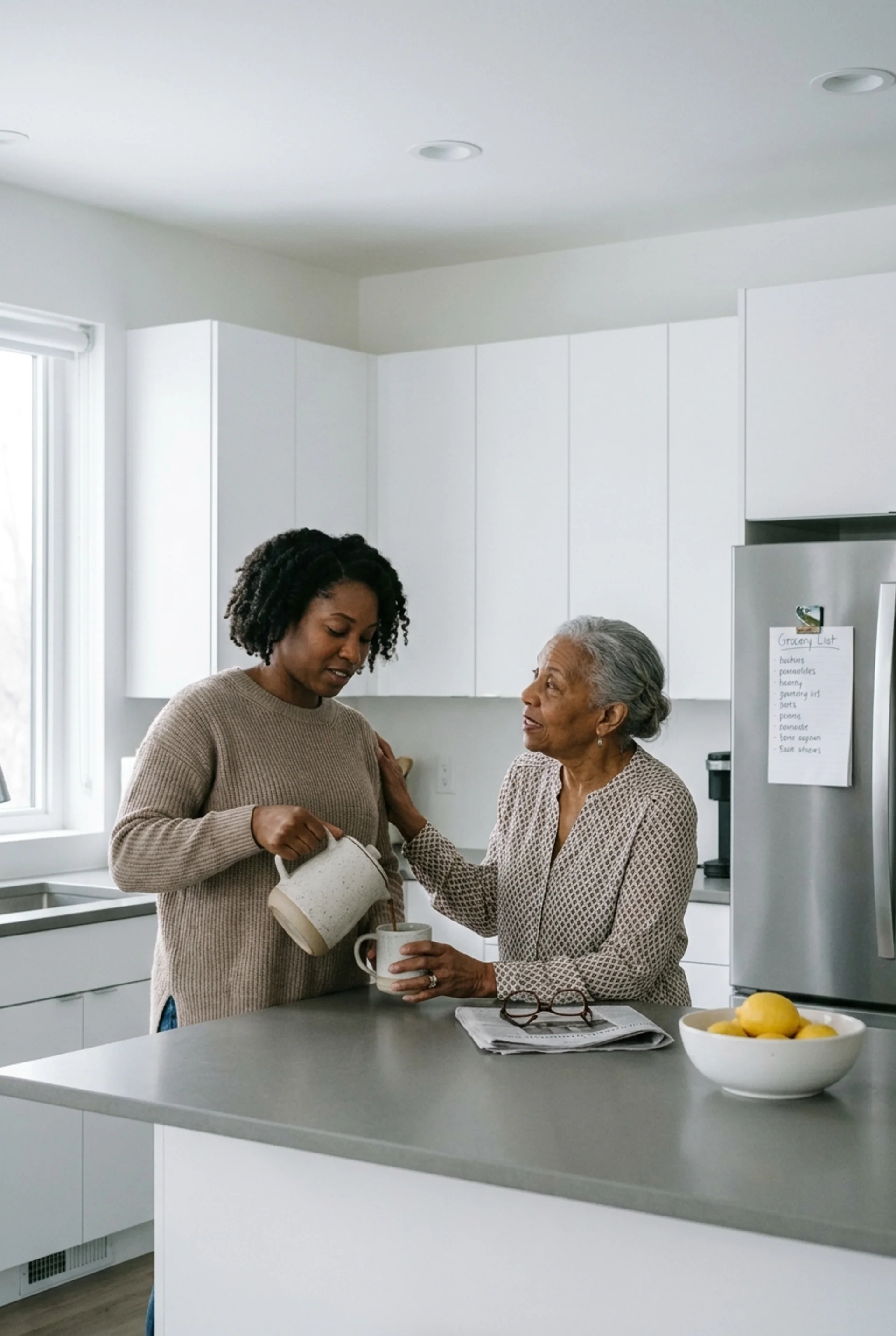 Adult daughter pouring coffee for her elderly mother in a bright kitchen